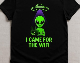 May include: Black t-shirt featuring a green alien holding a router under a purple beam from a UFO. The text "I CAME FOR THE WIFI" is printed in green below the alien. The design is a humorous take on extraterrestrial life.