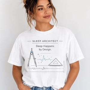 Peut inclure: Un t-shirt blanc à manches courtes avec un imprimé graphique noir et bleu. Le texte indique SLEEP ARCHITECT et Sleep Happens by Design. Le motif comprend un compas de dessin, une équerre et des lignes ondulées bleues.