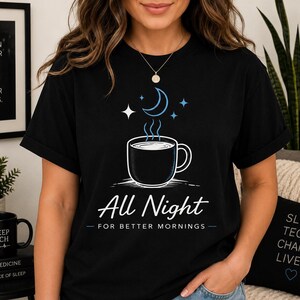 Könnte beinhalten: Ein schwarzes Kurzarm-T-Shirt mit einer Grafik aus einer dampfenden Tasse, einer Mondsichel und Sternen. Der Text lautet All Night FOR BETTER MORNINGS in Weiß und Blau. Das Design ist mittig auf der Brust des T-Shirts mit Rundhalsausschnitt platziert.