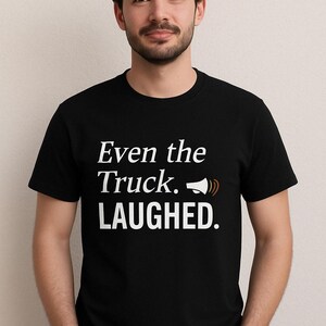 May include: A black t-shirt with white text that reads "Even the Truck. LAUGHED."  The text is accompanied by a small graphic of a megaphone.