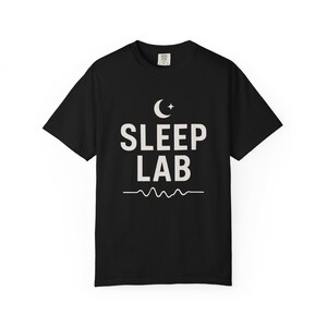 以下が含まれることがあります： 白い三日月、"SLEEP LAB"という文字、波打つ線が描かれた黒いTシャツ
