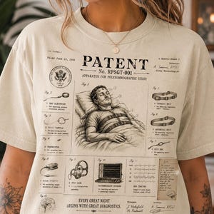 Könnte beinhalten: Ein beiges T-Shirt mit einem schwarzen Grafikdruck einer alten Patentzeichnung für ein polysomnographisches Untersuchungsgerät. Das Design zeigt technische Diagramme medizinischer Geräte, eine zentrale Figur im Bett sowie den Text Patent No. RPSGT-001 und Every Great Night Begins With Great Diagnostics.