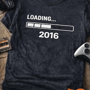 May include: Dark gray t-shirt with the text "LOADING... 2016" in white. The design includes a loading bar graphic. Additional text includes "READY TO DOWNLOAD LOADING... 2016 PNG & SVG".
