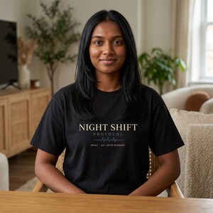 Könnte beinhalten: Schwarzes T-Shirt mit dem Text "NIGHT SHIFT PROTOCOL" in einer Serifenschrift. Darunter befindet sich eine stilisierte Herzschlag-Grafik und der Text "RPSGT - EST. AFTER MIDNIGHT". Das T-Shirt wird von einer Person getragen.
