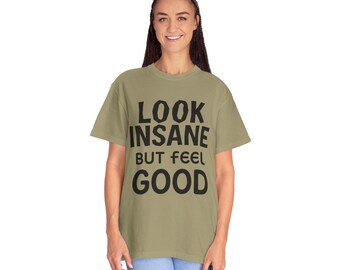 Könnte beinhalten: Hell olivgrünes T-Shirt mit dem Text "LOOK INSANE BUT FEEL GOOD" in fetten schwarzen Buchstaben. Das Shirt ist ein lässiger Stil, geeignet für den Alltag.