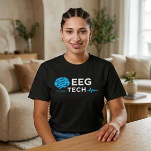 May include: A black t-shirt with the white text "EEG TECH", a blue brain graphic, and a blue heartbeat line. The t-shirt is worn by a person.