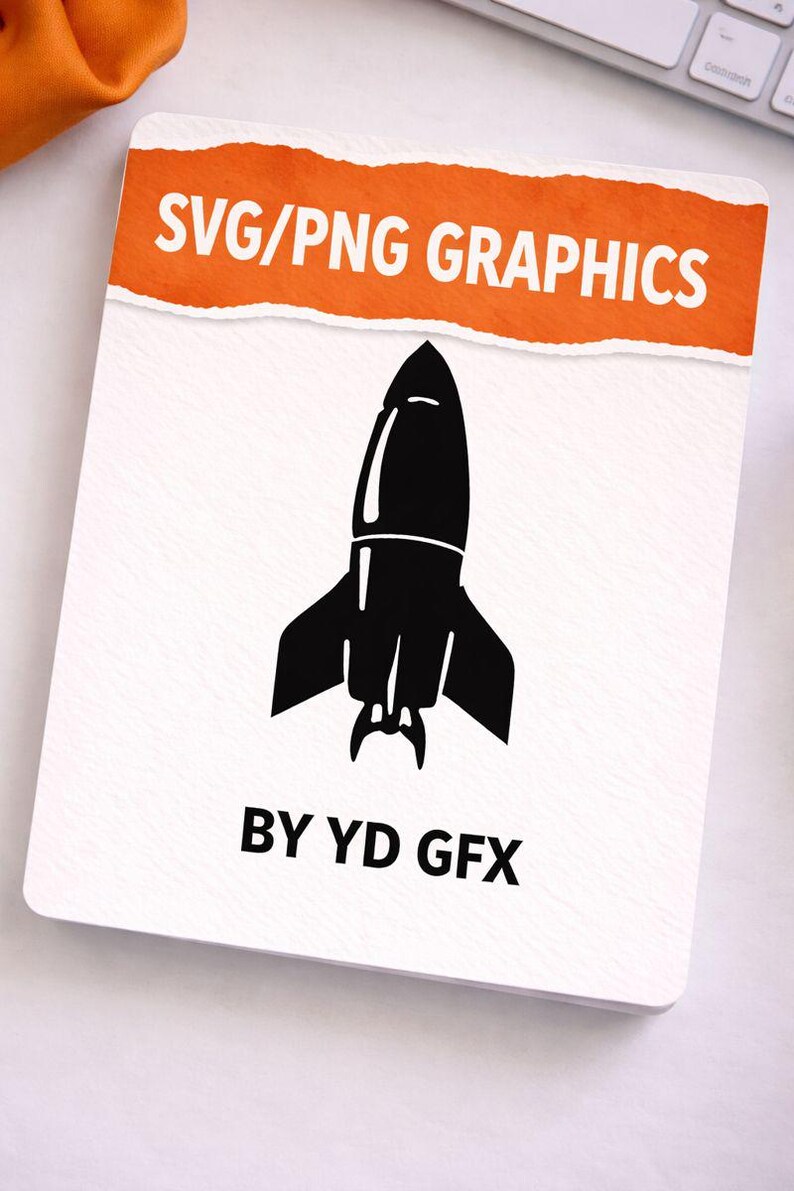 May include: A white card featuring a black rocket graphic. The top has an orange banner with "SVG/PNG GRAPHICS." The text "BY YD GFX" is at the bottom. The image is on a white surface.