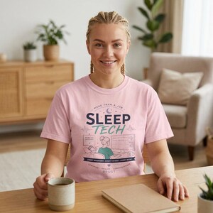 Peut inclure: Un t-shirt rose clair avec les mots "SLEEP TECH" en bleu marine et sarcelle. Le t-shirt comporte un graphique d'une personne travaillant sur un ordinateur. Le texte "MORE THAN A JOB" et "EVERY WAVEFORM, EVERY PATIENT, EVERY NIGHT" figurent également sur le t-shirt.