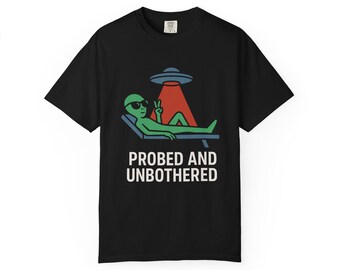 May include: Black t-shirt featuring a green alien wearing sunglasses, lounging on a chair, with a peace sign. Above the alien is a red beam of light from a UFO. The text "PROBED AND UNBOTHERED" is printed below the alien.