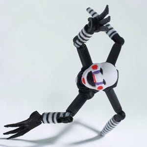 May include: A posable action figure featuring a white mask with red circular cheeks, purple tear-like markings, and a wide black mouth. The figure has a black torso, long black limbs with white striped segments, and three-fingered black hands.