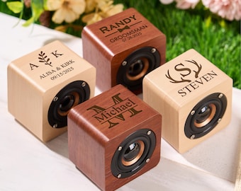 Puede incluir: Cuatro altavoces cúbicos de madera personalizados. Dos son de madera clara, dos de madera oscura. Cada altavoz tiene un altavoz negro y está grabado con nombres y fechas. Uno dice "ALISA & KIRK 09/15/2025". Otro dice "RANDY GROOMSMAN 07.28.2025".