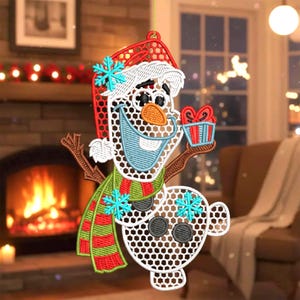 May include: Embroidered snowman Christmas ornament. The snowman wears a red hat, green and red scarf, and holds a gift. The ornament has a white, openwork design with blue snowflake accents. A festive holiday decoration.
