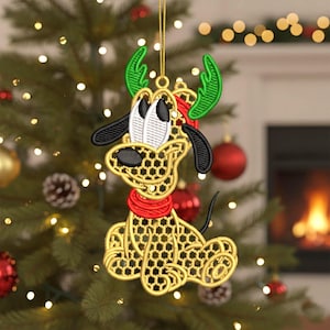 May include: Embroidered Christmas ornament featuring a cartoon dog character with reindeer antlers. The ornament is gold with black accents, a red scarf, and green antlers. It hangs from a gold string against a Christmas tree background.