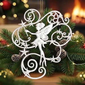 Può includere: Un ornamento natalizio a forma di fata bianca in filigrana con dettagli a stella e una bacchetta. La fata è circondata da disegni a spirale e stelle. L'ornamento è esposto su un letto di aghi di pino verdi con pigne e luci.