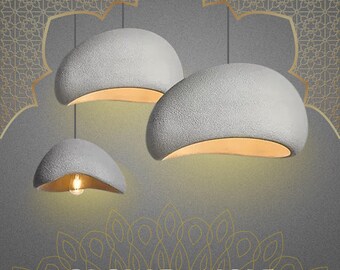 May include: Three gray, textured pendant lights with a curved, dome-like shape and a warm, golden interior. The lights are suspended from the ceiling, with the text "GLOW DANGLE" at the bottom of the image.