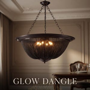 Op de afbeelding: Een bronzen kroonluchter met een komvormige kap van geweven materiaal. De armatuur hangt aan kettingen en heeft binnenverlichting. De tekst "GLOW DANGLE" staat onderaan de afbeelding.