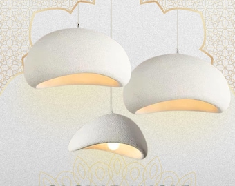 May include: Three white, textured pendant lights with a warm glow emanating from the bottom. The lights are suspended from the ceiling against a patterned background. The text "GLOW DANGLE" is at the bottom.