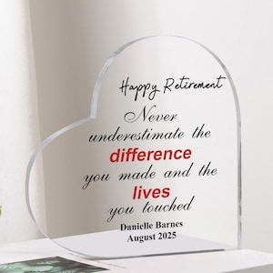 Può includere: Una targa in acrilico trasparente a forma di cuore con le parole "Happy Retirement" e un messaggio personalizzato. Il testo è in nero e rosso, con il nome "Danielle Barnes" e la data "Agosto 2025" in basso. La targa è esposta su una superficie bianca.