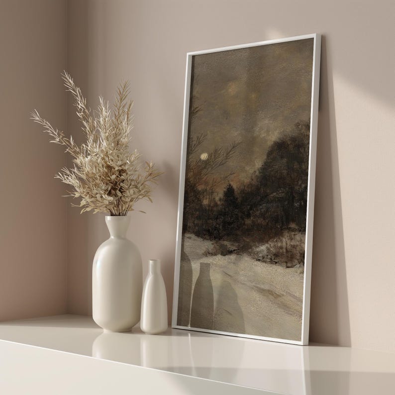 May include: A white framed painting of a snowy landscape with a moon in the sky. The painting is hanging on a light brown wall above a white shelf with two white ceramic vases.