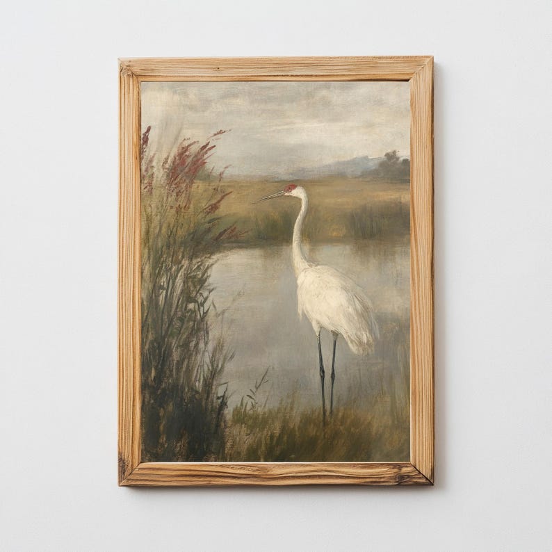 May include: A framed painting depicting a white crane standing in a marsh, with tall grasses and a body of water in the background. The sky is a muted grey with hints of blue.