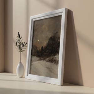 May include: A framed painting of a snowy landscape with a full moon in the sky. The painting is in a white frame and is hanging on a wall.