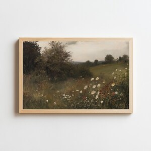 May include: A framed landscape print featuring a field of wildflowers and tall grass. The artwork has a vintage aesthetic with a muted color palette of greens, browns, and whites. The print is in a light-colored wooden frame.