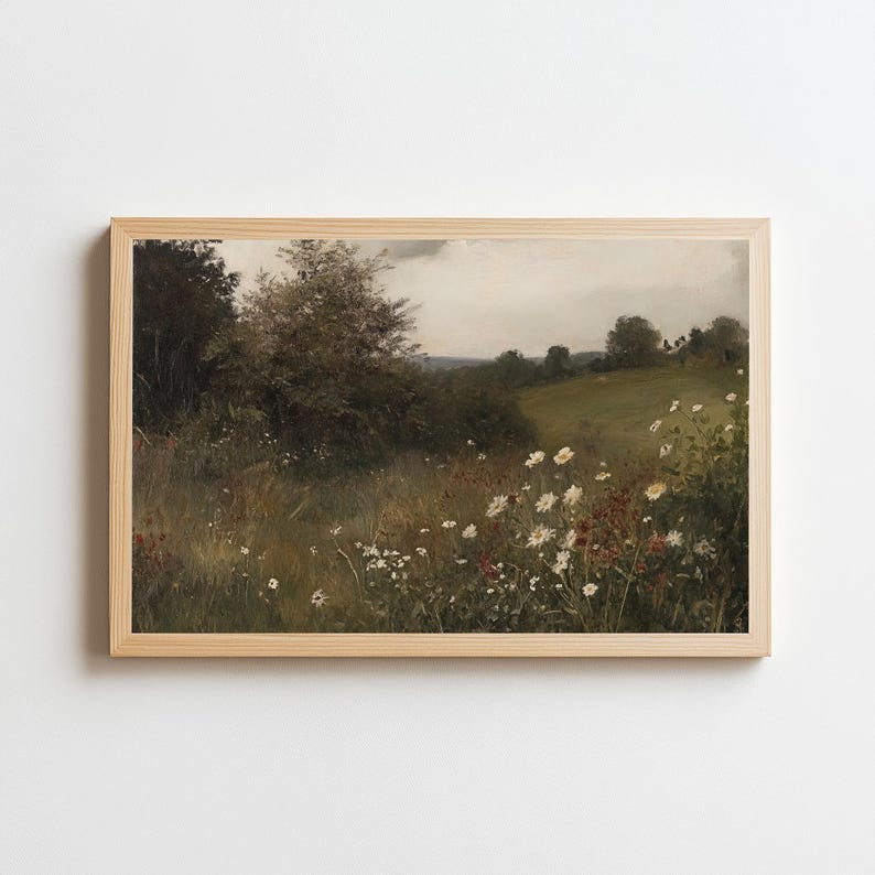 May include: A framed landscape print featuring a field of wildflowers and tall grass. The artwork has a vintage aesthetic with a muted color palette of greens, browns, and whites. The print is in a light-colored wooden frame.