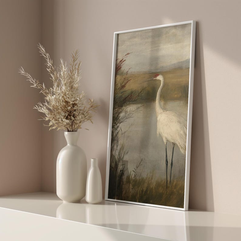 May include: A framed painting of a white crane standing in a marsh with brown and green reeds. The background is a hazy blue and white sky.