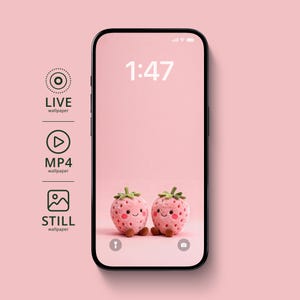 May include: A smartphone displays a pink wallpaper featuring two smiling strawberry plushies. The time 1:47 is shown at the top. The phone's screen is surrounded by a black frame, with icons for live, MP4, and still wallpapers on the left.