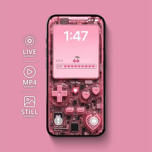 Op de afbeelding: Een roze handheld spelcomputer met een transparante behuizing die de interne circuits toont. Het scherm toont de tijd 1:47, een kersenicoon en een met hartjes gevulde ervaringsbalk. De knoppen bevatten een D-pad en hartvormige knoppen.