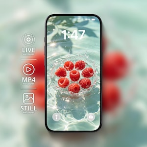 Puede incluir: Un teléfono inteligente que muestra un fondo de pantalla digital de frambuesas rojas salpicando en agua clara. La pantalla muestra la hora 1:47 e iconos para LIVE wallpaper, MP4 wallpaper y STILL wallpaper a la izquierda, con iconos de linterna y cámara.