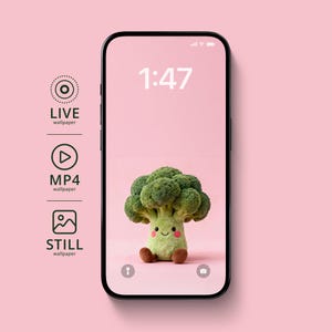 May include: A smartphone displays a wallpaper featuring a plush broccoli character with a smiling face and brown feet against a pink background. The time 1:47 is displayed at the top. Icons for live, MP4, and still wallpapers are on the left.