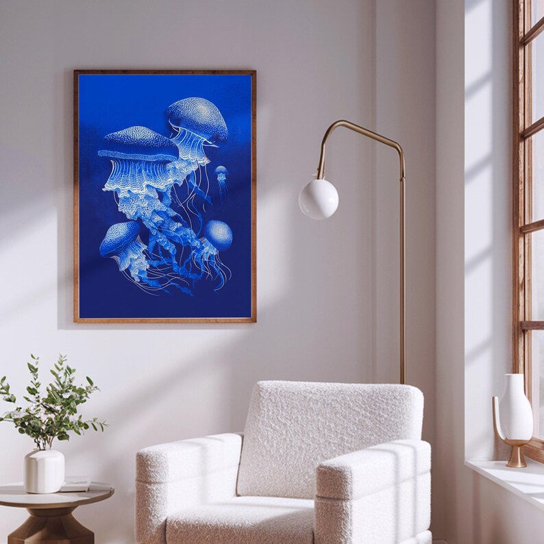 May include: A framed art print featuring a detailed illustration of several jellyfish in shades of blue and white against a deep blue background. The artwork is displayed in a room with a white chair and a gold floor lamp.