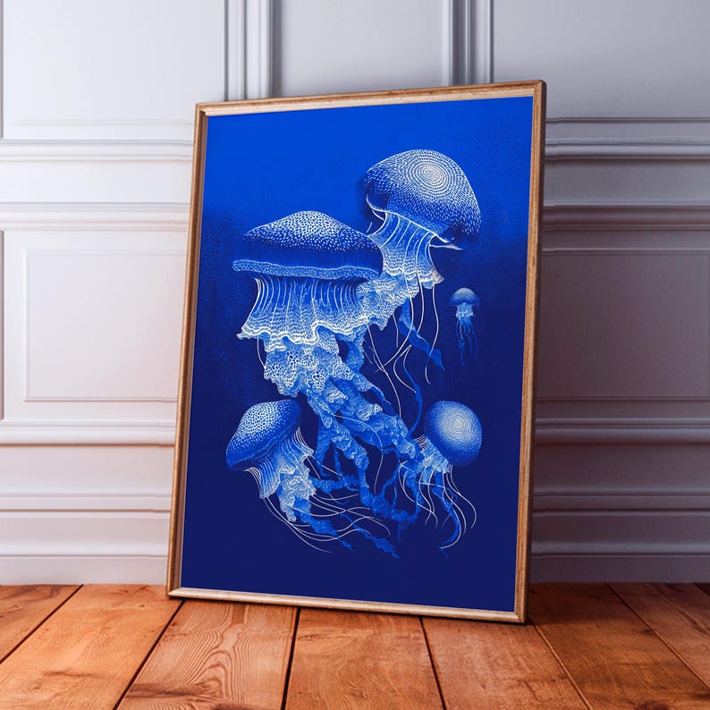 May include: A framed art print featuring a detailed illustration of several jellyfish in shades of white and blue against a deep blue background. The artwork is displayed in a wooden frame and leans against a wall.