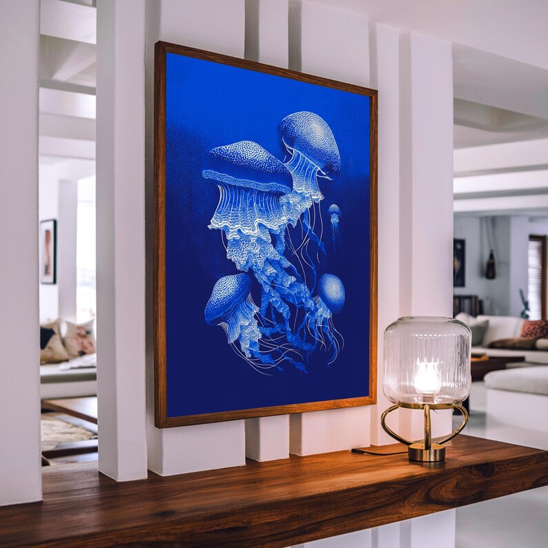 May include: A framed art print featuring a cluster of white jellyfish against a deep blue background. The jellyfish have detailed, flowing tentacles. The artwork is displayed on a wooden shelf, with a glass and brass lamp nearby.