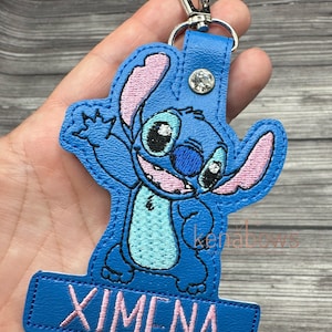 May include: Blue and pink embroidered Stitch character keychain with a blue leather tag that says "XIMENA".