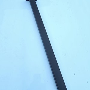 May include: A single, black, metal table leg. The leg is rectangular with a square mounting plate at the top, featuring four screw holes. The bottom of the leg is cut at an angle. The leg is approximately 30 inches long.