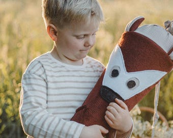 May include: A cone-shaped fabric gift container designed as a fox with a rust-colored body, white face accents, and dark brown eyes and nose. The top features a light-colored fabric closure with drawstring ties, creating a decorative fox-themed item.