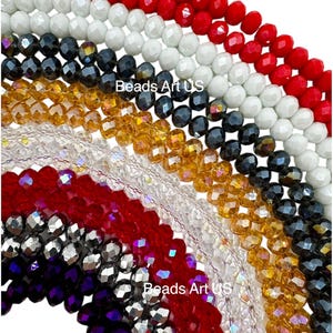 May include: Assortment of faceted glass beads in various colors, including red, white, black, gold, clear, and purple. The beads are arranged in a rainbow pattern, with the red beads at the top and the purple beads at the bottom. "Beads Art US" is written on the image.
