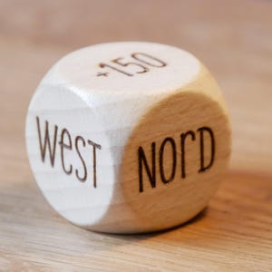May include: A wooden dice with the words "West" and "Nord" and the number "150" engraved on it.