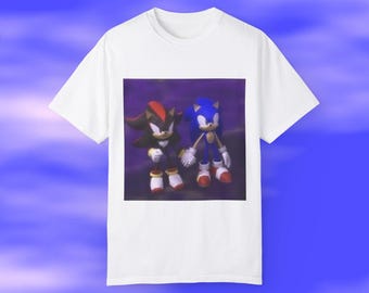 Può includere: Maglietta bianca con un'immagine stampata di Sonic the Hedgehog e Shadow the Hedgehog in piedi uno accanto all'altro. L'immagine è su uno sfondo viola.