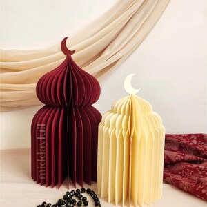 May include: Two paper mosque-shaped decorations, one cherry red and one cream, each topped with a crescent moon. A black prayer beads with gold accents lies in front. The text "Cherry and Cream Bundle" is at the top.
