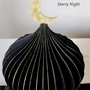 May include: A closeup of black decorative mosque dome with gold accents and a gold crescent moon on top. The text "Starry Night" is visible on the right side of the image. The product is from middaylull.