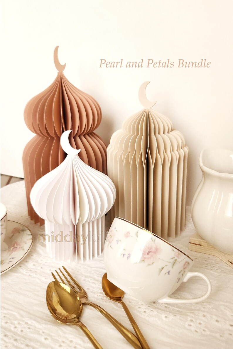 May include: A display of paper lanterns in white, beige, and brown, each with a crescent moon detail. A floral teacup, gold cutlery, and a white jug are also present. The text "Pearl and Petals Bundle" is visible in the image.