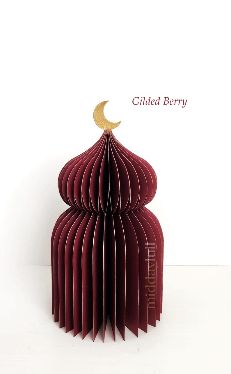 May include: A burgundy paper dome-shaped decoration with a gold crescent moon on top. The text "Gilded Berry" is visible. The paper structure is made of many vertical, curved panels.