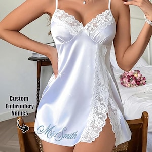 May include: White satin slip dress with lace trim and spaghetti straps. The dress features a split hem and custom embroidery that reads "Mrs. Smith". The text "Custom Embroidery Names" is also visible.
