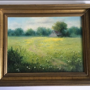 May include: A framed oil painting depicting a rural landscape with a white farmhouse in the distance, surrounded by a field of yellow wildflowers and green grass.