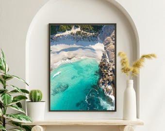 Può includere: Vista aerea di una spiaggia di sabbia bianca con acqua turchese e scogliere rocciose. L'acqua è limpida e poco profonda, e la spiaggia è circondata da una lussureggiante vegetazione verde.