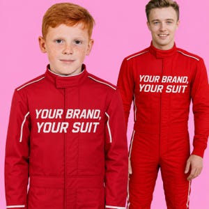 May include: Two red racing suits with high collars and white piping details. The text "YOUR BRAND, YOUR SUIT" is printed in white on the chest of each suit. The suits feature a front zipper closure and long sleeves, designed for a uniform appearance.