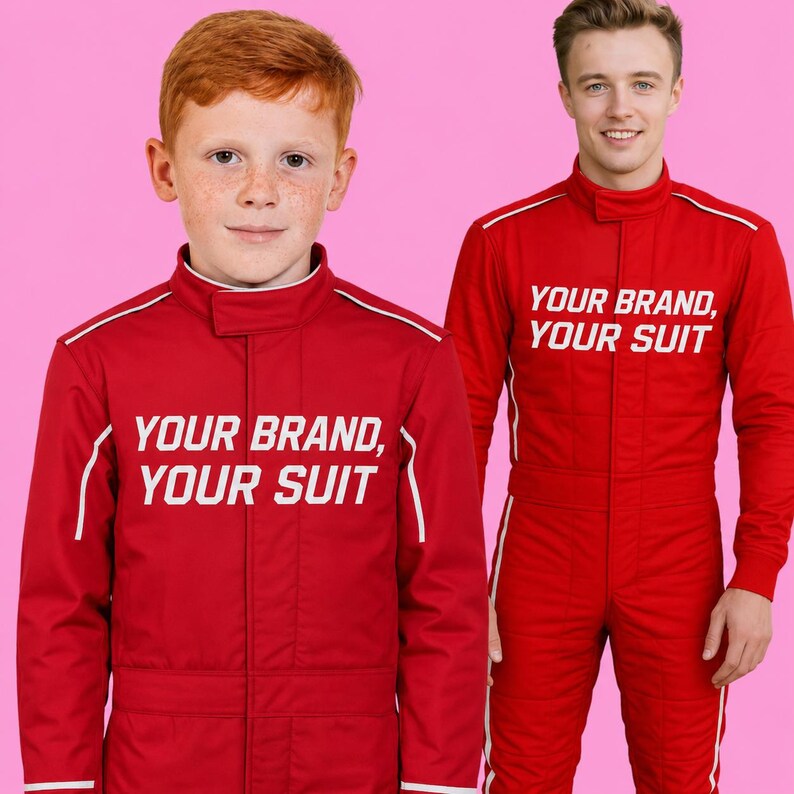 May include: Two red racing suits with high collars and white piping details. The text "YOUR BRAND, YOUR SUIT" is printed in white on the chest of each suit. The suits feature a front zipper closure and long sleeves, designed for a uniform appearance.
